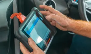 Mechanik używa podręcznego komputera diagnostycznego w samochodzie.