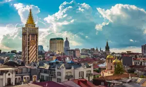 Widok na miasto Batumi, Gruzja, z charakterystyczną wieżą zegarową i złotymi kopułami cerkwi pod błękitnym, chmurowym niebem.
