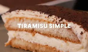 Une part généreuse de tiramisu simple, parfait pour 10 personnes, avec ses couches de biscuits imbibés et de crème onctueuse, saupoudré de cacao.