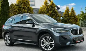 Elegancki, ciemnoszary BMW X1 na tle nowoczesnego domu. Sprawdź atrakcyjną bmw x1 cena!