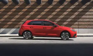 Czerwony Hyundai i30 Hatchback zaparkowany na tle ceglanej ściany z geometrycznymi cieniami.