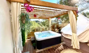 Jacuzzi extérieur sous pergola, décoré de cœurs, près d'une yourte dans les Alpes-Maritimes. Détente et nature.