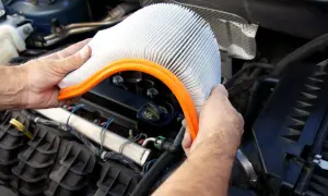 Main tenant, quand changer filtre à air. Un homme tient un filtre à air de voiture propre, prêt à le remplacer dans le compartiment moteur.
