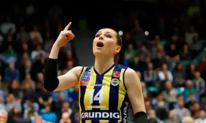 Eda Erdem, z numerem 14 na koszulce, wskazuje palcem w górę, krzycząc z radości na boisku siatkarskim.