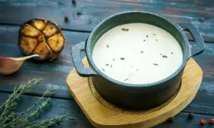 Cremoso alioli con leche, servido en cazuela de hierro fundido, acompañado de ajo asado y tomillo fresco.