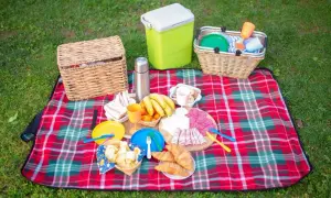 Co zabrac na piknik? Koszyk, lodówkę, koce, jedzenie: kanapki, owoce, wędliny, croissanty, napoje i naczynia.