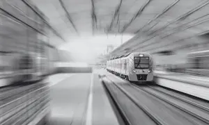Nowoczesny pociąg pędzi po torach, symbolizując szybki rozwój infrastruktury i wykup gruntów pod kolej.