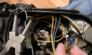 Wymiana żarówki w reflektorze Volvo V50. Widać narzędzia i przewody.