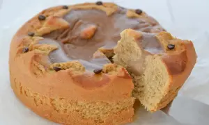 Torta al caffè ricette della nonna, soffice e profumata, con glassa al caramello e chicchi di caffè. Una fetta è già stata tagliata.