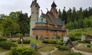 Drewniana świątynia Wang w Karkonoszach, otoczona cmentarzem i lasem.