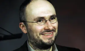 Uśmiechnięty mężczyzna w okularach, z zarostem. Sebastian Krajewski, którego życie prywatne budzi zainteresowanie, wygląda na zrelaksowanego.