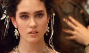 Jennifer Connelly w filmach, z burzą ciemnych włosów ozdobionych srebrnymi dodatkami i wyrazistym makijażem oczu.