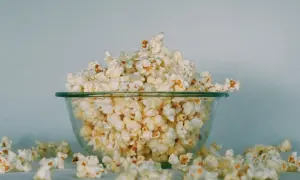 Miska pełna popcornu, rozsypanego wokół. Czy koty mogą jeść popcorn? To pytanie nurtuje wielu właścicieli.