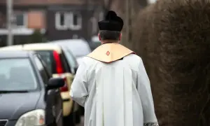 Ksiądz w sutannie i birecie odchodzi od samochodów. Co się mówi do księdza na dowidzenia? "Szczęść Boże!