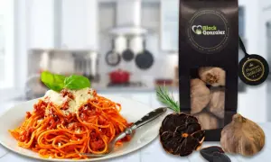 Spaghetti mit Tomatensoße, daneben eine Packung schwarzer Knoblauch und ganze Knoblauchzehen. Perfekt für schwarzer Knoblauch Rezepte.
