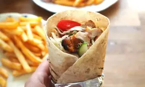 Pyszny kebab z kurczakiem, warzywami i frytkami na talerzu. Idealny posiłek na szybki lunch.