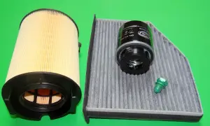 Zwei Auto-Filter (Öl- und Innenraumfilter) und eine grüne Schraube auf grünem Hintergrund.