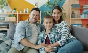 Szczęśliwa rodzina: tata, mama i syn siedzą na kanapie. Choć nie da się określić, ile kosztuje dziecko, miłość i radość są bezcenne.