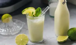 Erfrischende brasilianische Limonade mit Limettenscheiben und Minze, daneben eine Flasche und frische Limetten.