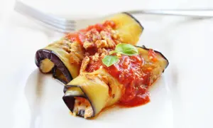 Deliziosi involtini di melanzane alla siciliana, ripieni e conditi con sugo rosso e basilico fresco, pronti per essere gustati.