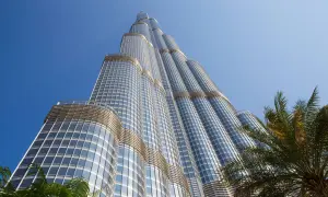 Burj Khalifa, najwyższy budynek na świecie, wznosi się ku błękitnemu niebu, otoczony palmami.