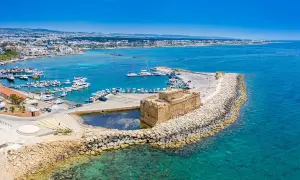 Zamek w Paphos, Cypr, nad turkusowym morzem. W tle port z łodziami i miasto. Idealne miejsce na wakacje, blisko lotniska.