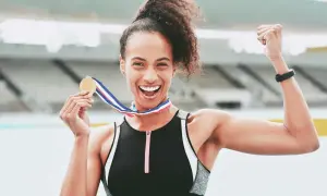 Atleta felice con medaglia d'oro dopo la corsa 10 km. Celebra la vittoria con un pugno alzato.