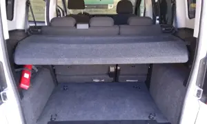 Interni del Fiat Qubo con sedili posteriori abbassati e vano bagagli spazioso. Si intravede un estintore rosso.
