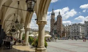 Podcienia Sukiennic w Krakowie, z widokiem na Rynek Główny i Kościół Mariacki. Stare miasto Kraków tętni życiem.