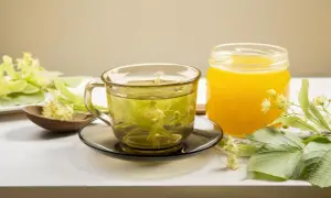 Aromatyczna herbata z lipy w szklance, obok słoik miodu i świeże kwiaty lipy.