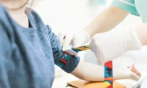 Pielęgniarka zakłada opaskę uciskową na ramię pacjentki, aby pobrać krew do badań, np. kiedy progesteron badac.