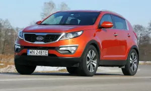 Pomarańczowy Kia Sportage 2012 na drodze, z widocznym numerem rejestracyjnym WN 2481E.