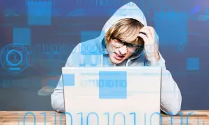 Młody mężczyzna w kapturze zmagający się z problemem, zastanawia się, adware co to jest. Cyfrowy kod otacza go.