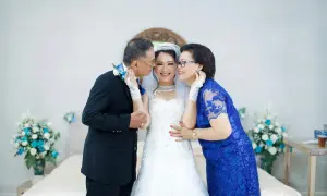 Rodzice szepczą mądre życzenia ślubne młodej parze. Uśmiechnięta panna młoda w białej sukni, ojciec w garniturze, matka w niebieskiej sukience.