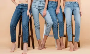 Cztery kobiety w różnych odcieniach jeansów siedzą na stołkach. Denim to materiał, który nigdy nie wychodzi z mody.