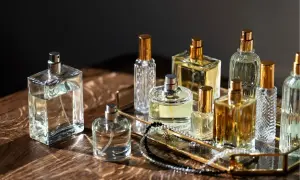 Kolekcja flakonów perfum, w tym Estee Lauder Modern Muse, na złotej tacy z biżuterią.