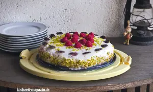 Himbeer Joghurt Torte mit frischen Beeren und Pistazien, verziert mit Schokoladenherzen. Ein Genuss für jeden Anlass.