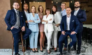 Grupa profesjonalistów w eleganckich garniturach i kostiumach pozuje do zdjęcia.