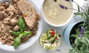 Kotlet mielony z kaszą, grzybami i surówką, obok miseczka zupy i lawenda.