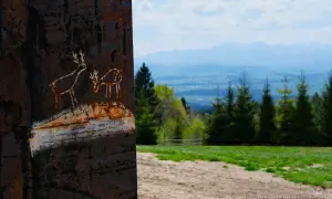 Rdzawy słup z rysunkami jeleni, z widokiem na góry i las. Może to początek najkrótszy szlak na Turbacz?