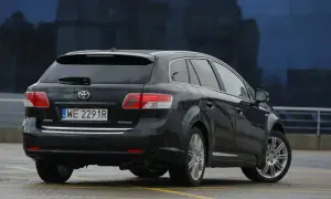 Czarna Toyota Avensis T27, kombi, z widocznym tyłem i tablicą rejestracyjną. Może być pomocna przy wymianie żarówki.