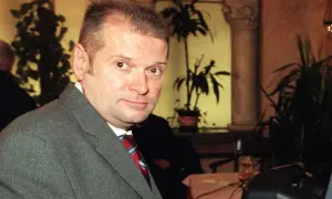 Rutkowski kiedys, w szarym garniturze i czerwonym krawacie, z uwagą patrzy w obiektyw.