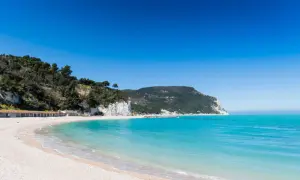 Spiagge San Benedetto del Tronto: sabbia chiara, mare cristallino e scogliere verdi sotto un cielo azzurro.