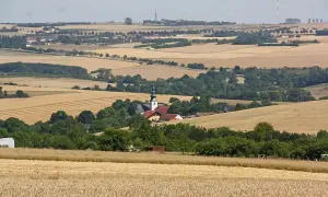 Wie wiele kościół ma ziemi w Polsce? Widok na wieś z kościołem i polami zbóż.