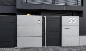 Nowoczesne ogrodzenie murowane z betonowych płyt i ciemnoszarych paneli. Numer domu 55.
