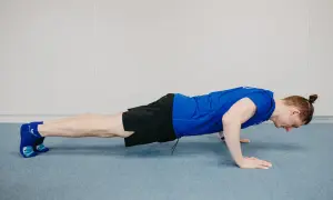 Mężczyzna wykonuje ćwiczenie diamond push ups, z dłońmi złączonymi pod klatką piersiową.