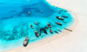 Widok z lotu ptaka na turkusową wodę i białą plażę, gdzie cumuje wiele łodzi. Idealne miejsce na malediwy loty.