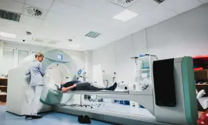 Pacjent leży na stole do badań, a technik przygotowuje się do wykonania scyntygrafii kości.