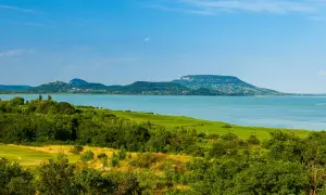Malowniczy krajobraz z jeziorem Balaton na Węgrzech, zielone wzgórza i błękitne niebo.