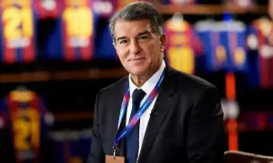 Joan Laporta, prezydent FC Barcelona, w garniturze, z identyfikatorem klubu. W tle widoczne koszulki piłkarskie.